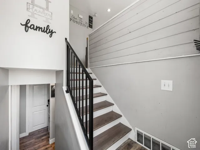 Staircase featuring wood-finish treads and risers, with a black metal railing