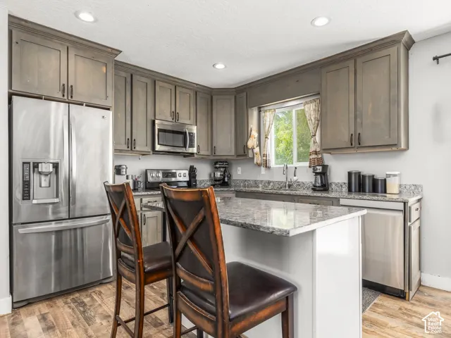 Wood-finish flooring with a kitchen island featuring a light-toned countertop