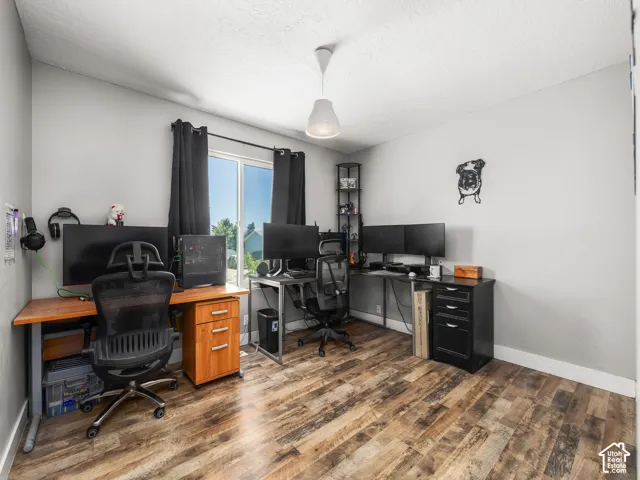 Room with wood-finish flooring, light gray wall paint, and a window with black curtains