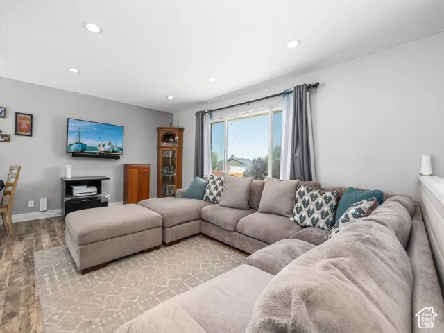Recessed lighting, wood-finish flooring, and a large window with curtain rods