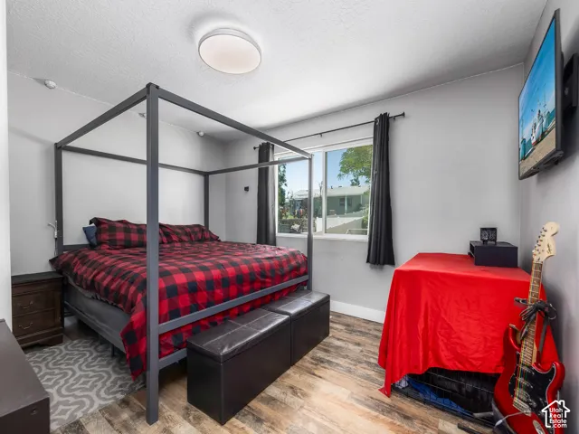 Wood-finish flooring, light gray wall paint, and a window with black privacy drapes