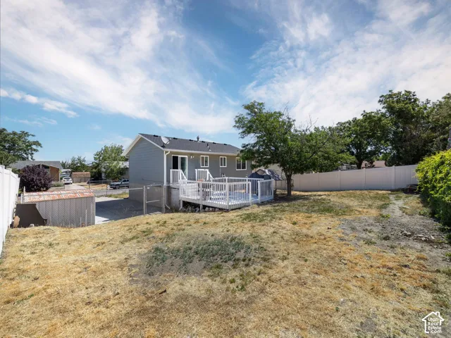 Expansive backyard featuring a white privacy fence, mature trees, and a ground-level patio with white railings