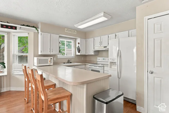 Kitchen featuring white cabinetry, a built-in kitchen island, and wood-finish flooring