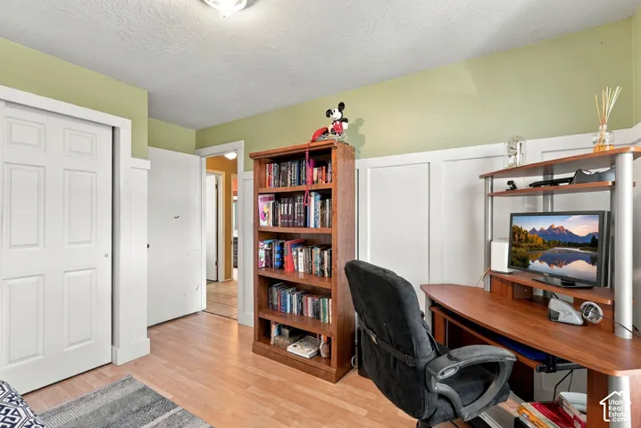 Light wood-finish flooring with white wainscoting and a flush-mount ceiling light