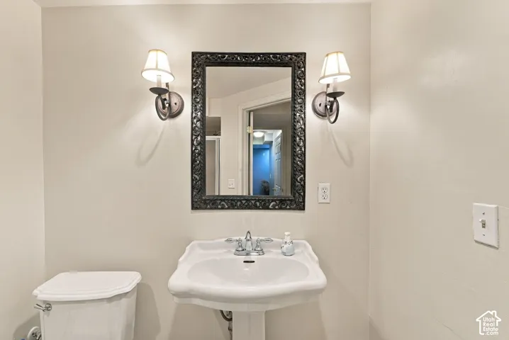 Pedestal sink with chrome-finish faucet, framed wall mirror, and dual wall sconces