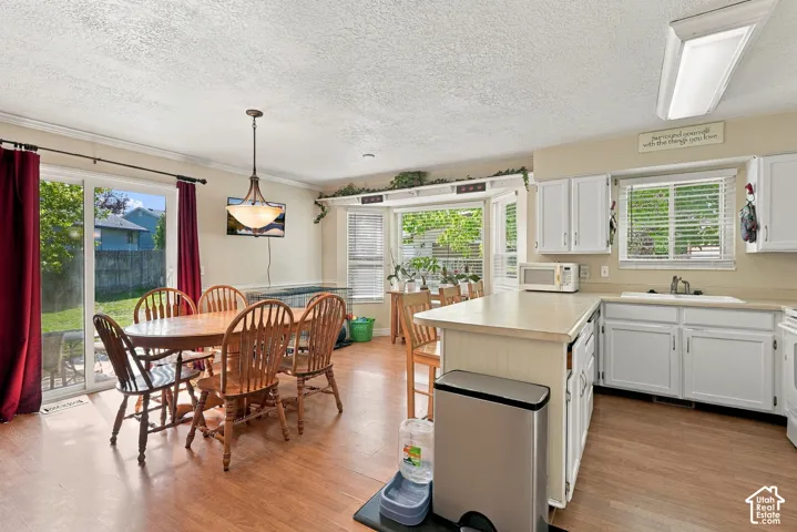 Kitchen and dining area featuring wood-finish flooring, white cabinetry, and a bay window