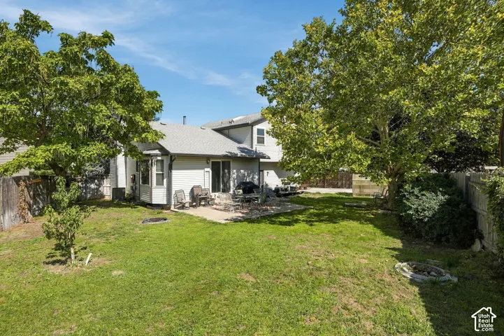 Expansive backyard featuring a manicured lawn, established trees, and a stone patio