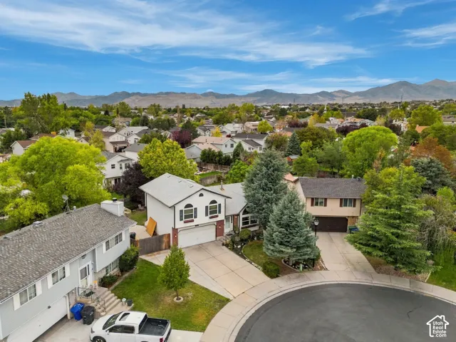 Cul-de-sac location with a concrete driveway, mature trees, and a mountain backdrop
