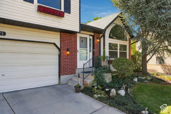 Brick and siding facade with an arched window, attached garage, and concrete driveway