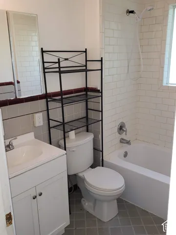 White subway tile shower surround with a built-in bathtub, and a single vanity with storage cabinetry