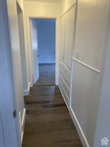 Hallway featuring wood-finish flooring, built-in storage cabinetry with drawers, and beadboard wall paneling