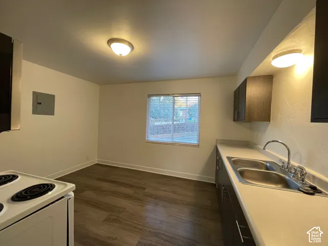 Kitchen area featuring wood-finish flooring, a double basin stainless steel sink, and upper and lower cabinetry with metal hardware
