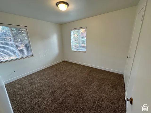Recessed ceiling light fixture, two windows with blinds, light-toned walls, and brown carpet flooring