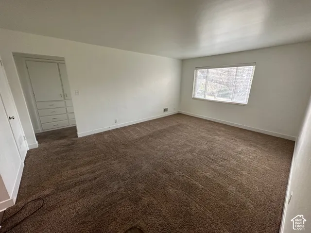 Spacious room featuring carpeting, a built-in storage cabinet, and a large window