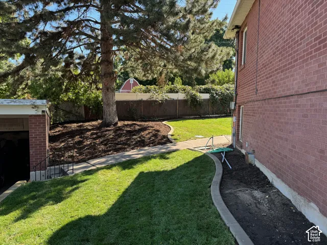 Red brick exterior with white trim, featuring a manicured lawn, mature trees, and a paved pathway