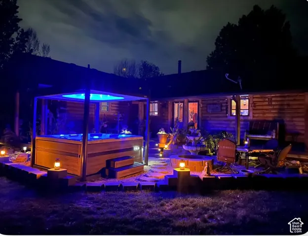 Outdoor spa with integrated lighting, wood-clad siding, and a stone-edged fire pit