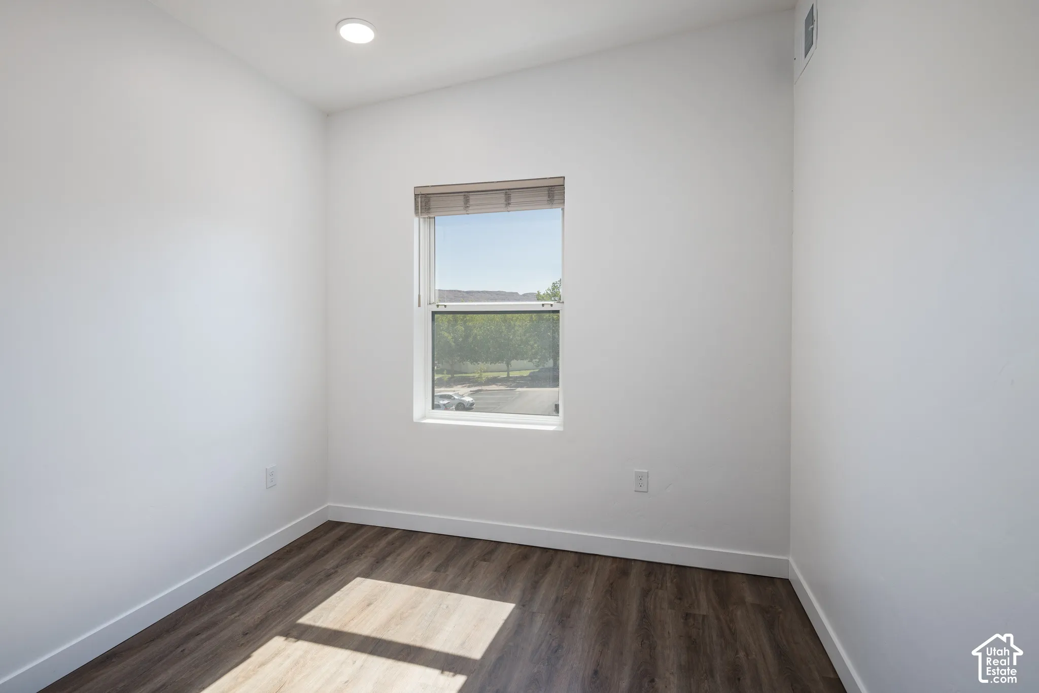 Recessed lighting, wood-finish flooring, white walls, and a window with blinds