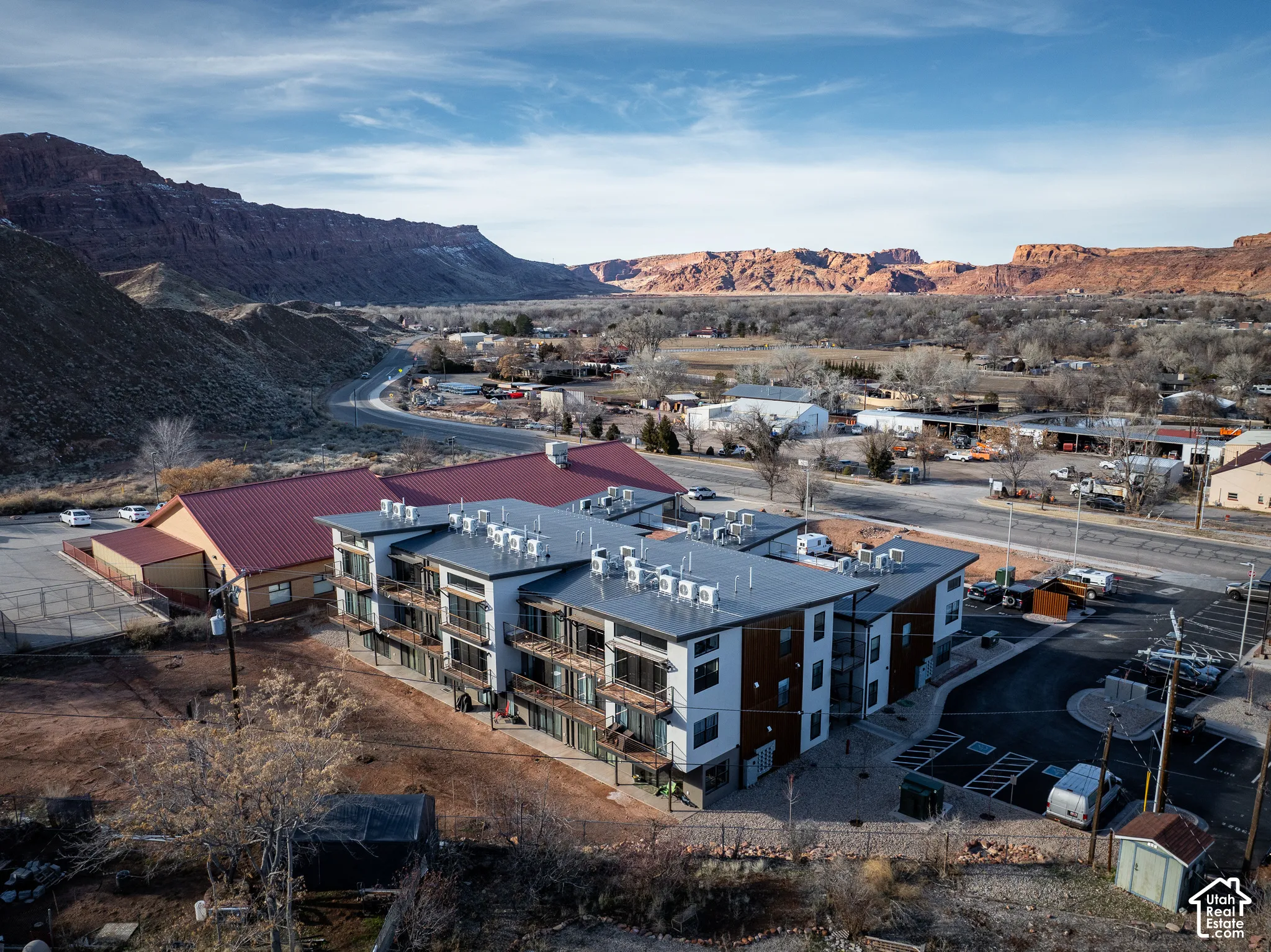 Modern multi-unit residential building featuring clean-lined architecture with mixed material exterior cladding, expansive windows, and ground-level parking