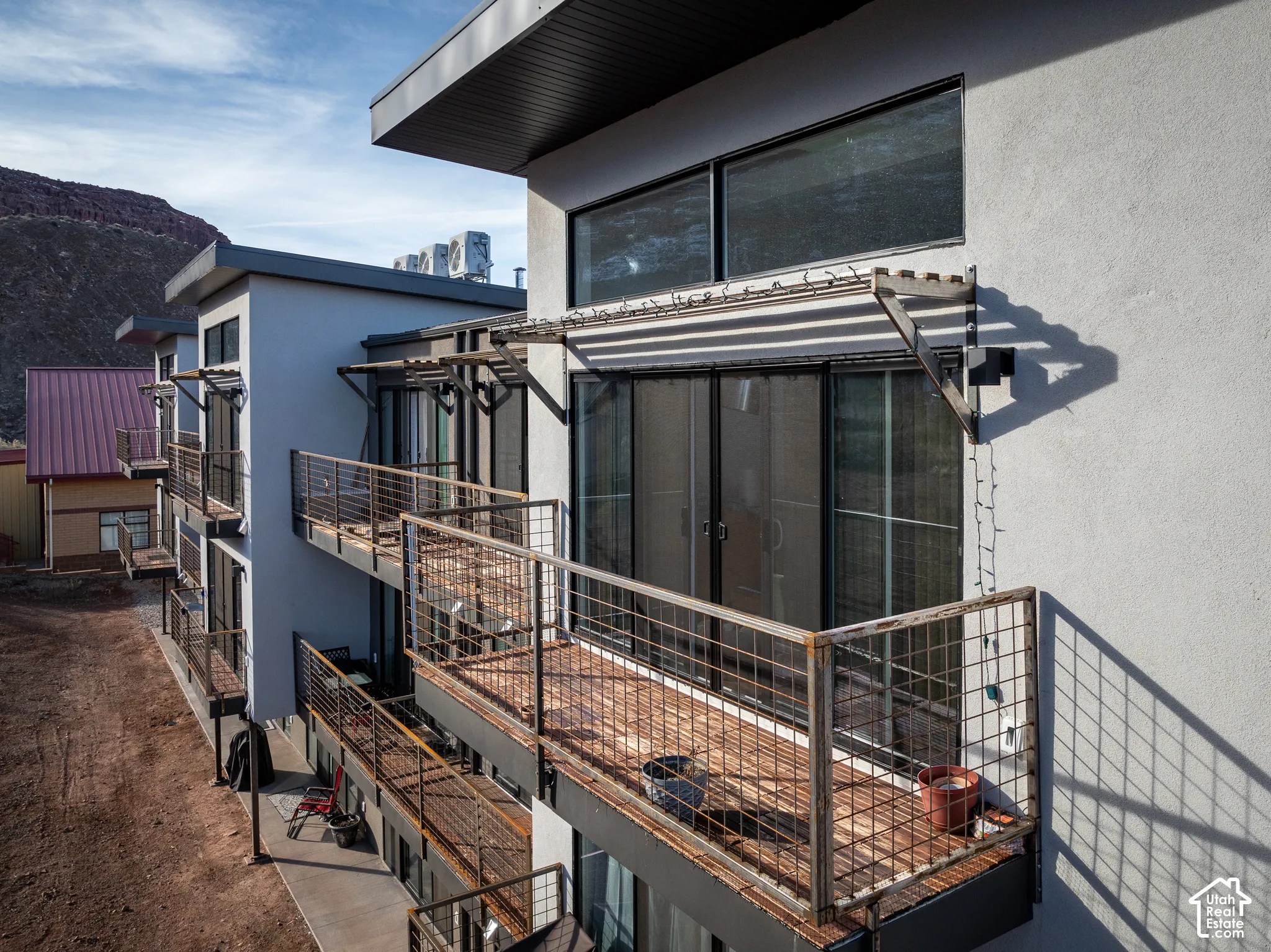 Multi-level building with individual balconies featuring metal grid railings and wood-finish flooring