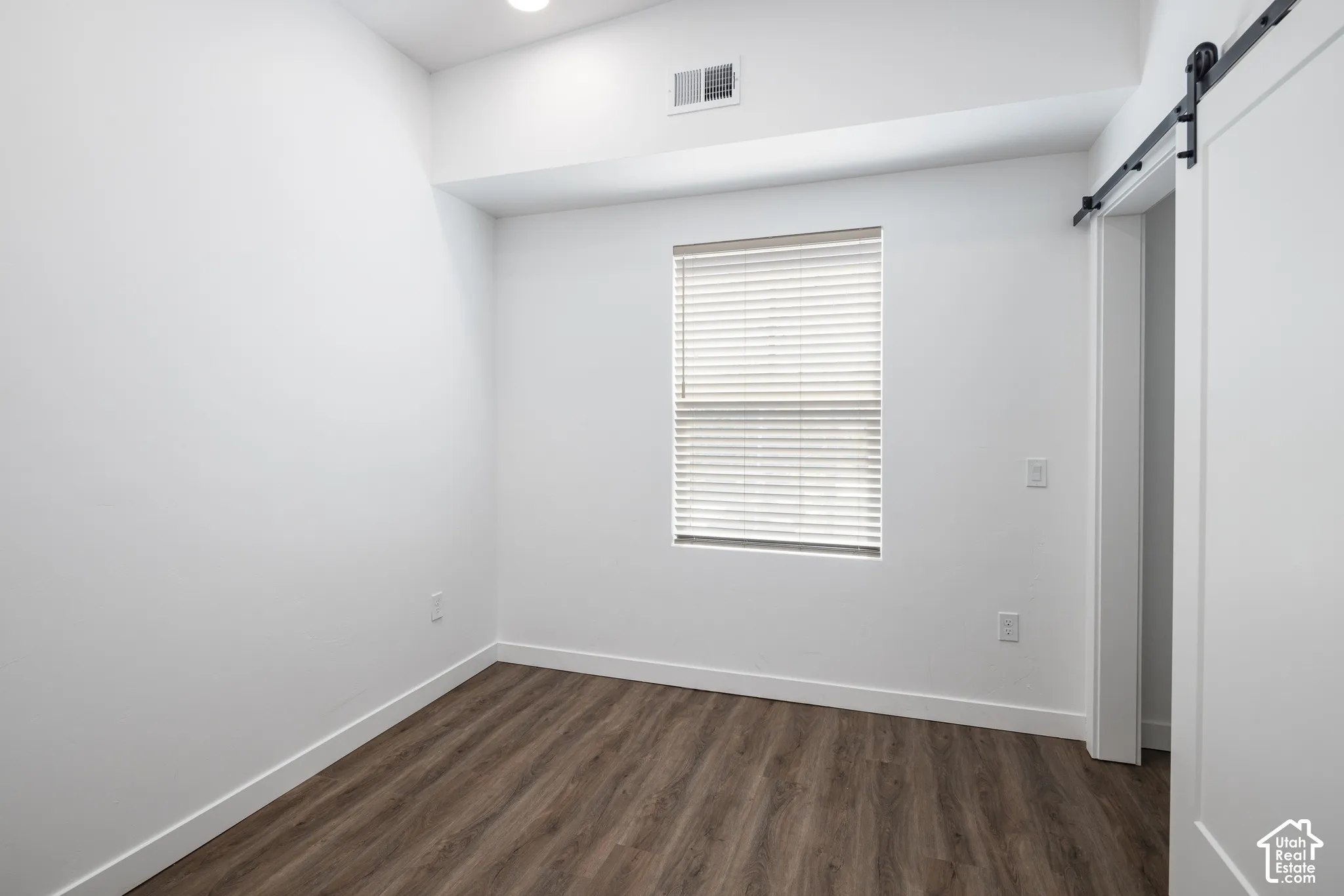 Recessed ceiling lighting, wood-finish flooring, window with blinds, and white walls