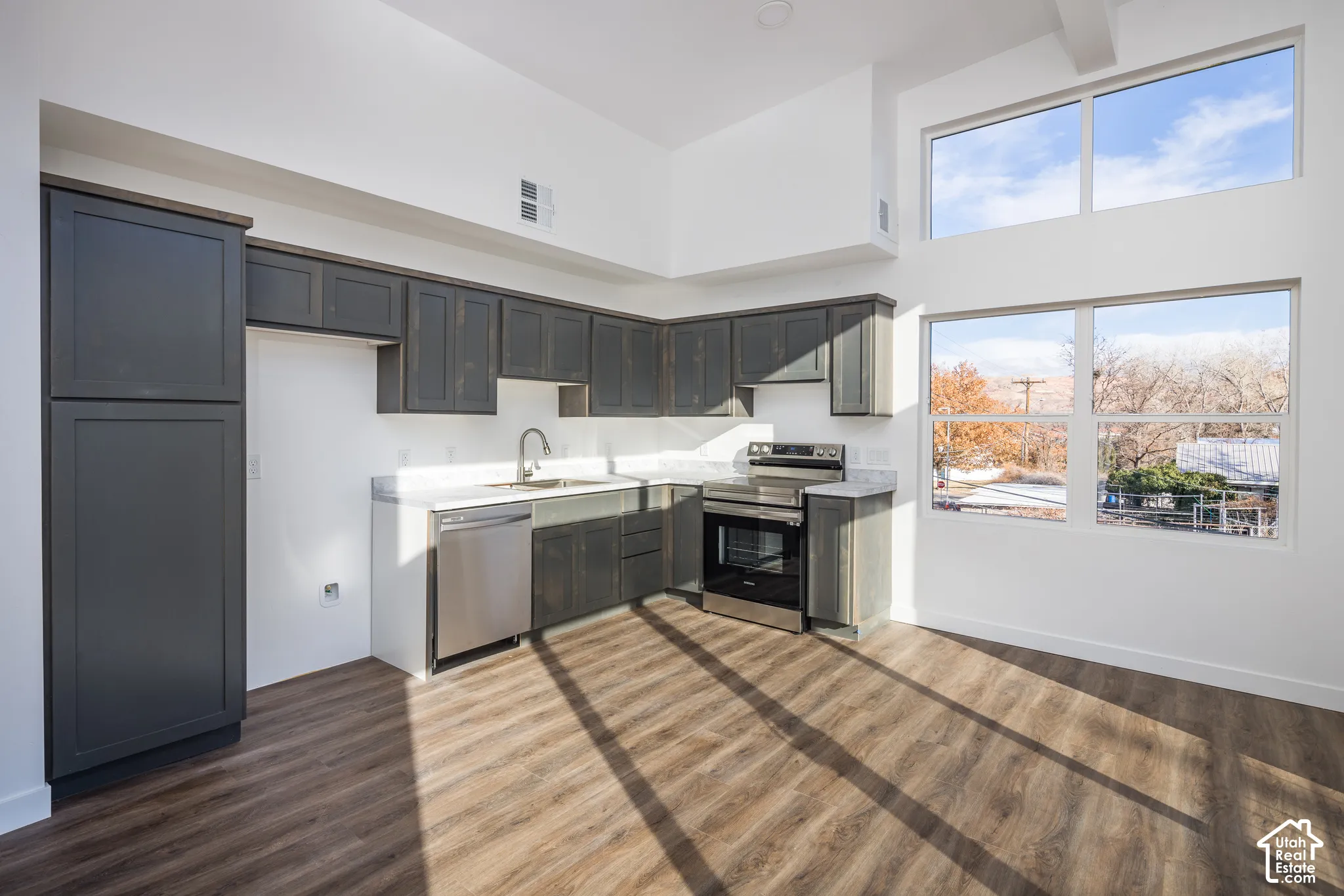 Kitchen featuring dark wood-finish cabinetry, light countertops, stainless steel appliances, and wood-finish flooring