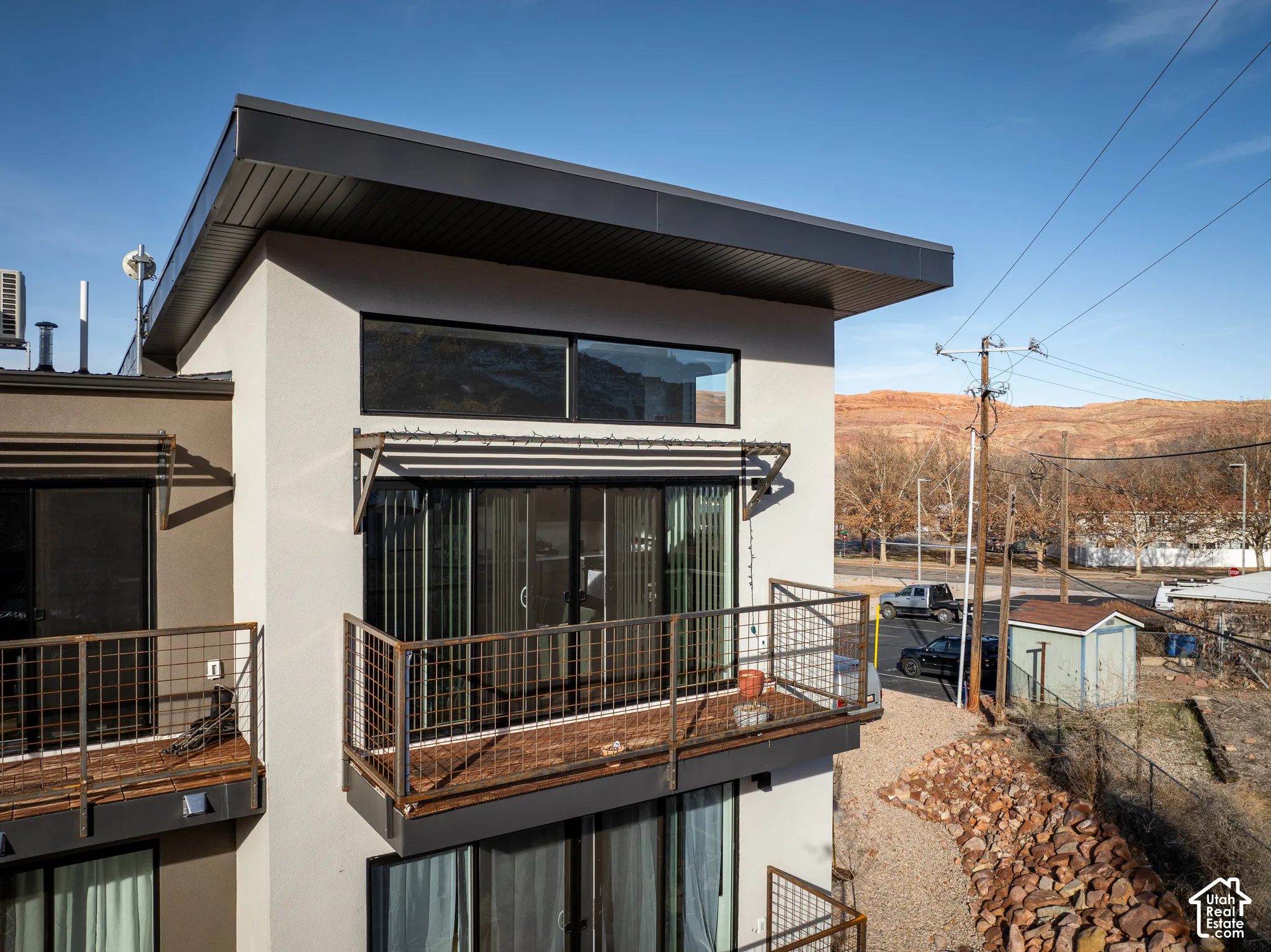 Modern exterior with a flat roof, multiple balconies, a sliding glass door, and upper-level windows