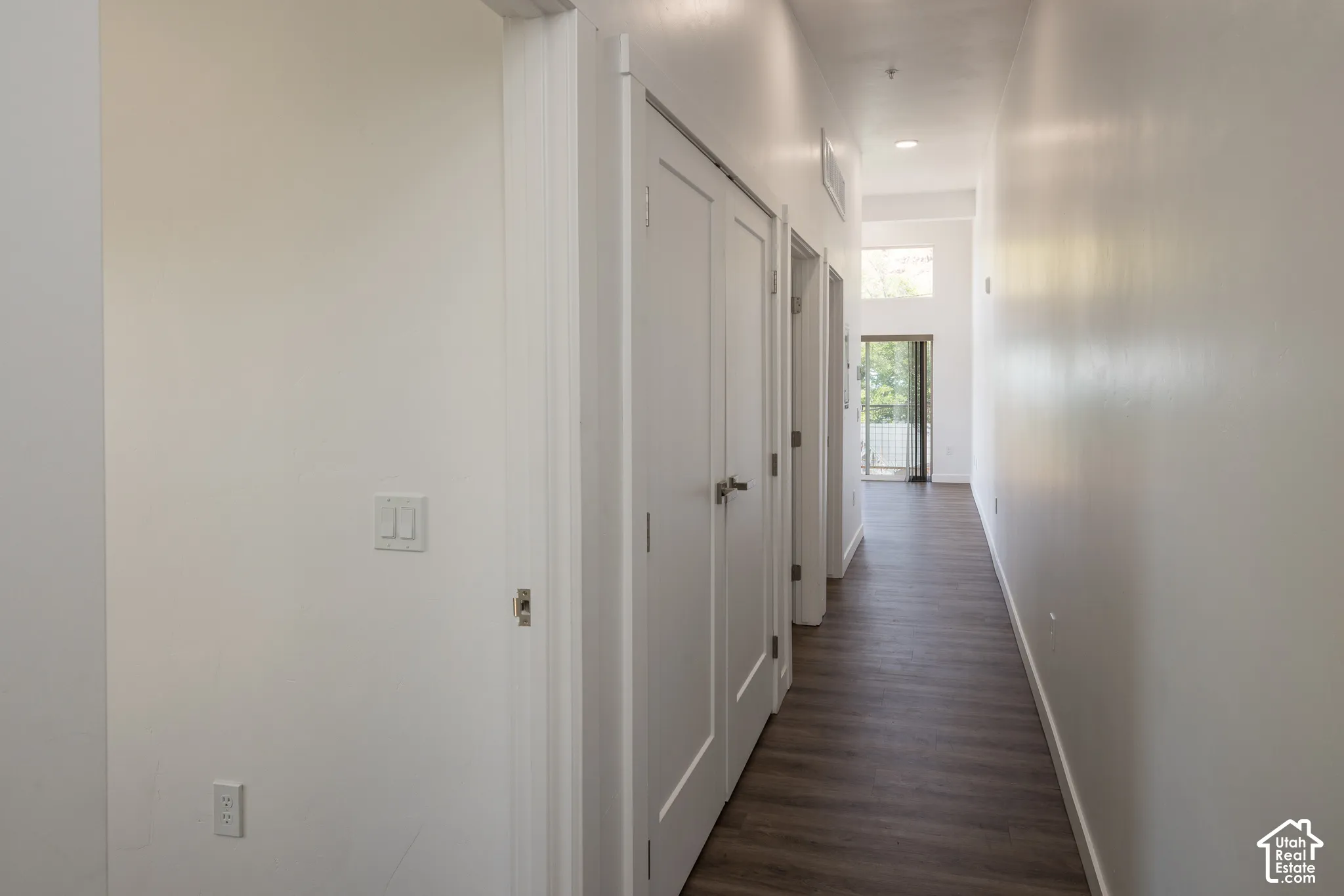 Hallway featuring wood-finish flooring, white walls, and recessed lighting