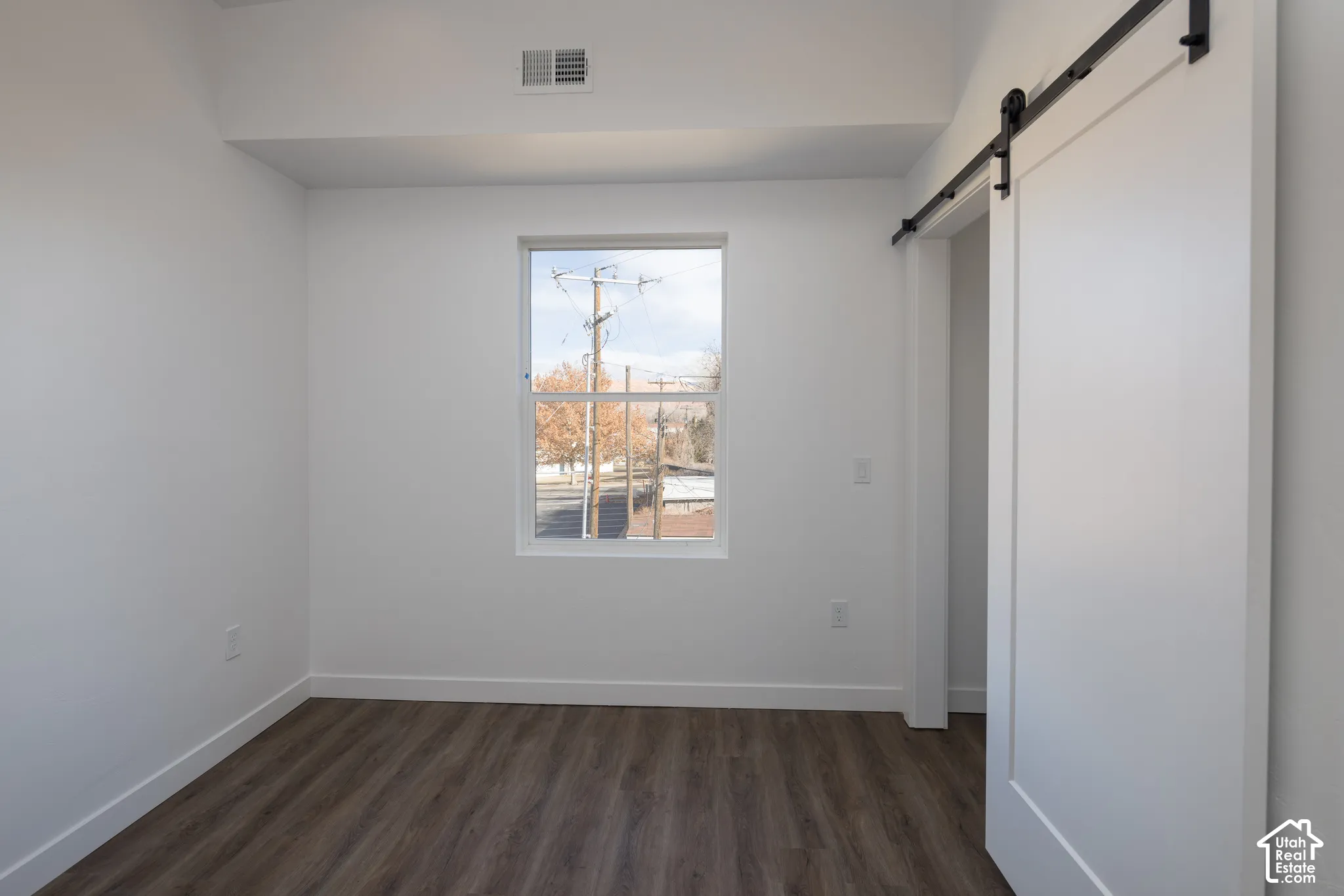 Wood-finish flooring, white walls, and a window with a white frame
