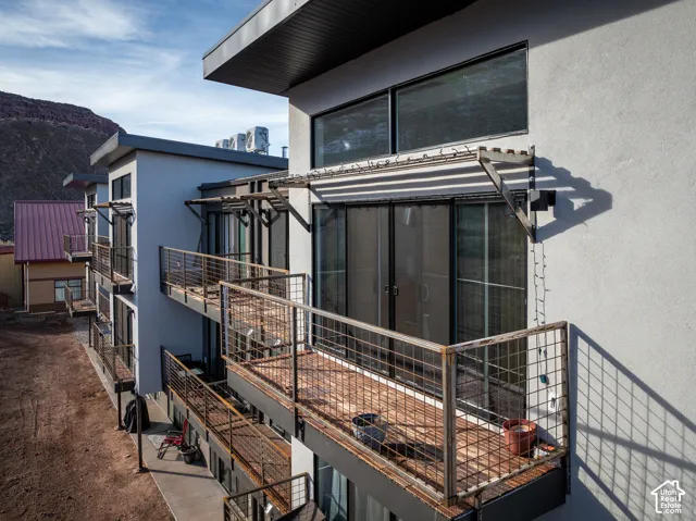 Multi-level building with individual balconies featuring metal grid railings and wood-finish flooring