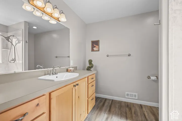 Extended vanity with light wood-finish cabinetry, integrated rectangular sink, and chrome-finish fixtures