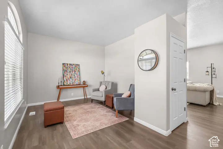 Vaulted ceiling, arched window, wood-finish flooring, white baseboards, and a paneled interior door