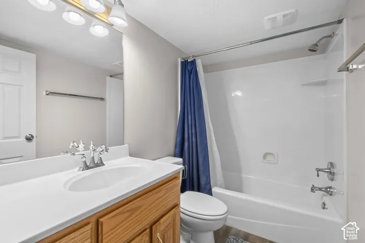 Bathroom featuring a light wood-finish vanity, integrated sink with chrome fixtures, full-width mirror, and a white tub/shower combination
