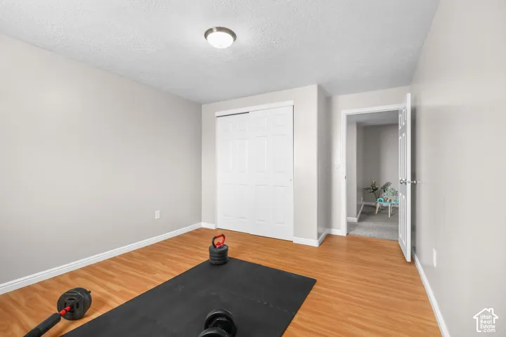 Smooth wall finish, wood-finish flooring, white trim, sliding closet doors, and recessed lighting