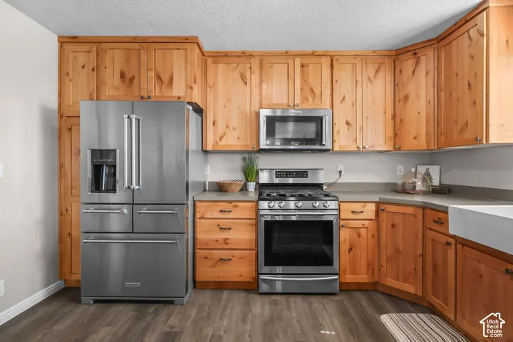 Wood-finish flooring, light wood cabinetry, stainless steel appliances, light-toned countertops, and a built-in microwave