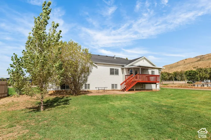 White siding exterior with a dark shingle roof, complemented by a red-painted elevated deck featuring a staircase
