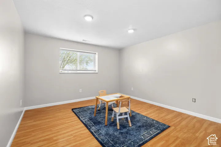 Recessed ceiling lighting, wood-finish flooring, neutral wall tones, window with blinds