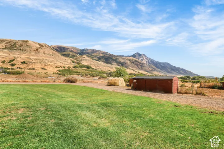 Expansive grassy area with a red outbuilding and a rounded storage structure, set against a mountainous backdrop