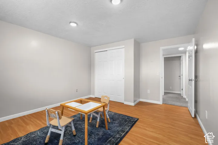 Recessed ceiling lighting, wood-finish flooring, white trim, sliding closet doors, and a paneled white door
