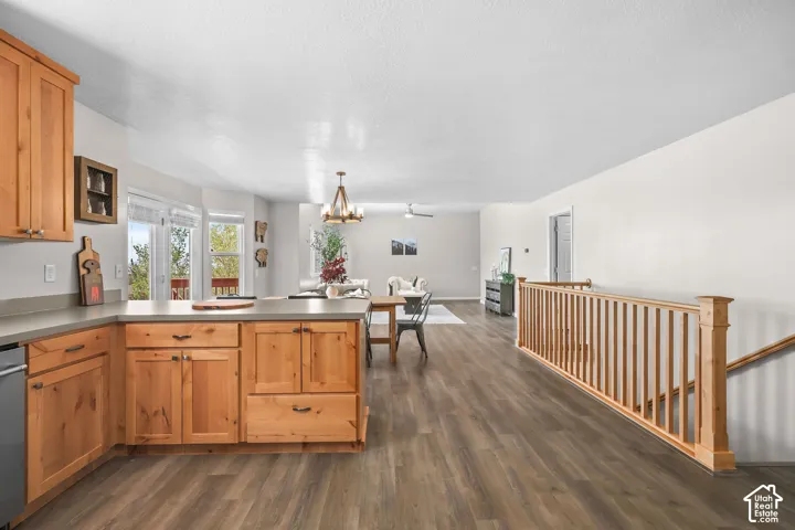 Wood-finish flooring throughout, natural wood cabinetry, light-toned countertops, and a wooden staircase with balustrade