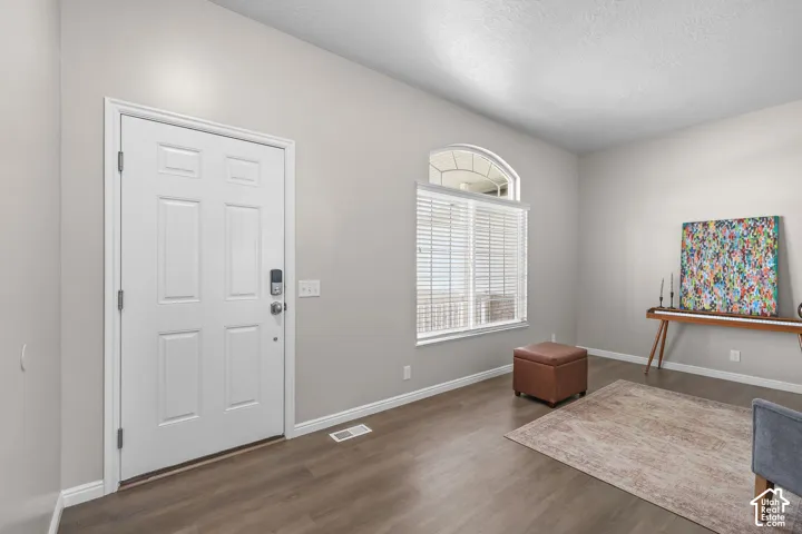 Entryway featuring a white paneled door with smart lock, wood-finish flooring, light gray walls, and a large window with an arched transom