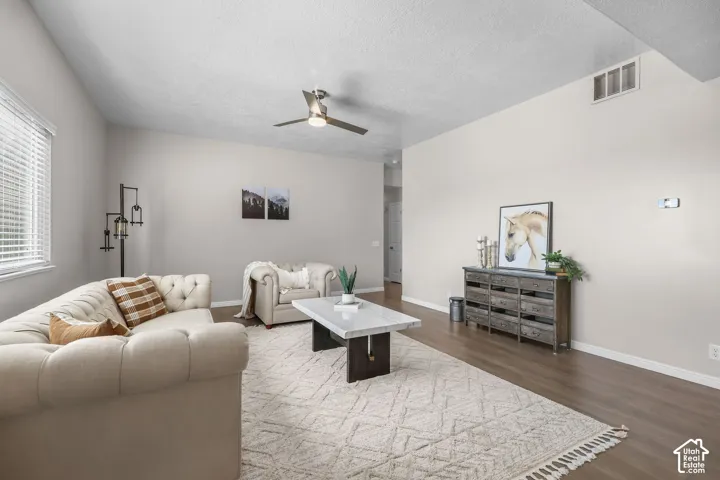 Vaulted ceiling with a contemporary ceiling fan, wood-finish flooring, neutral paint palette, and window with blinds