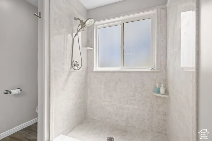 Shower enclosure with light-toned wall panels, a built-in corner shelf, and a sliding window