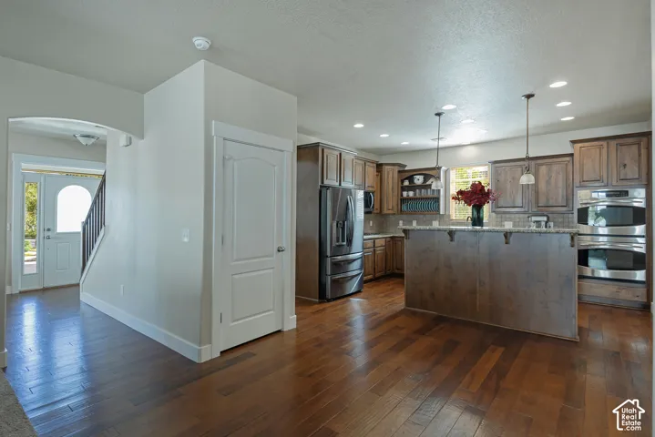 Kitchen featuring wood cabinetry, stainless steel appliances, a center island with pendant lighting, and recessed ceiling lights