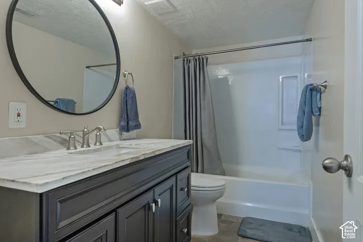 Bathroom featuring a dark wood finish vanity with a light-toned countertop, a white acrylic shower-tub combination, and a large round wall mirror