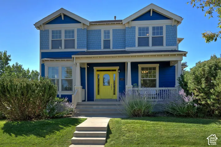 Two-story residence featuring a covered front porch, a bright yellow entry door, white trim, and a concrete walkway
