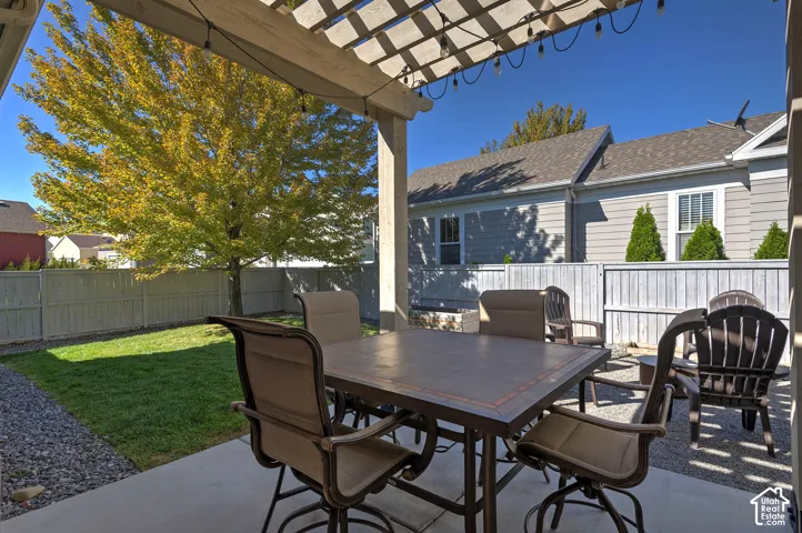 Covered patio with a wooden pergola, string lights, a concrete patio, and a gravel area