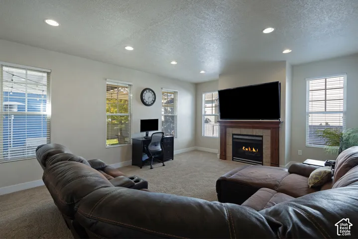 Recessed lighting, multiple windows, built-in gas fireplace with wood mantel, and a tiled surround
