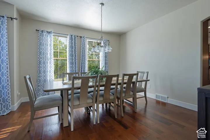 Hardwood-finish flooring with a multi-light chandelier and three windows with blinds