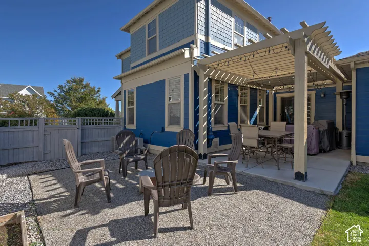 Private outdoor space featuring a pergola-covered patio, gravel ground cover, and full perimeter fencing