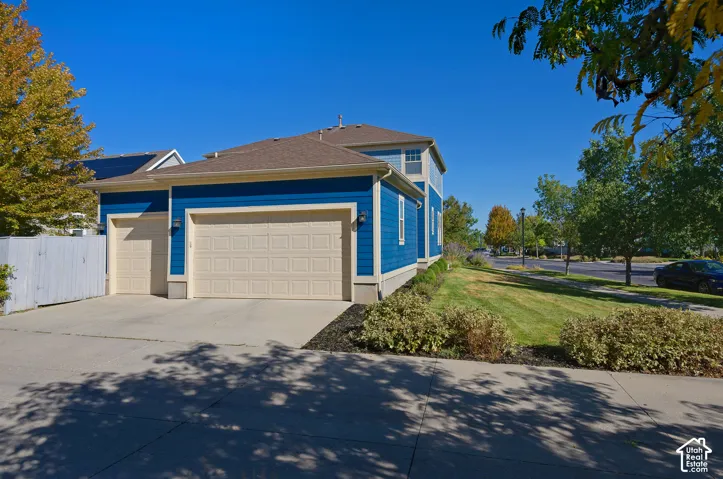 Two-car garage with concrete driveway, blue horizontal siding, white trim, and a manicured lawn